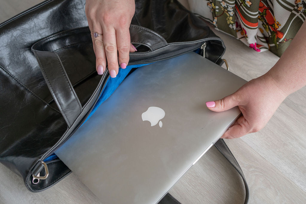 Person holding a 15" laptop with an Apple logo inside a black bag.