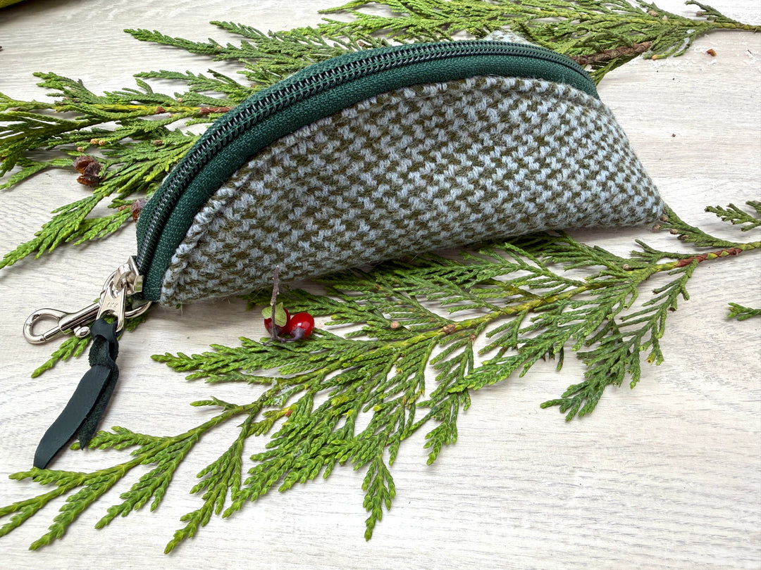 Fabric pouch with a zipper on a branch with leaves and berries #color_forest-tweed