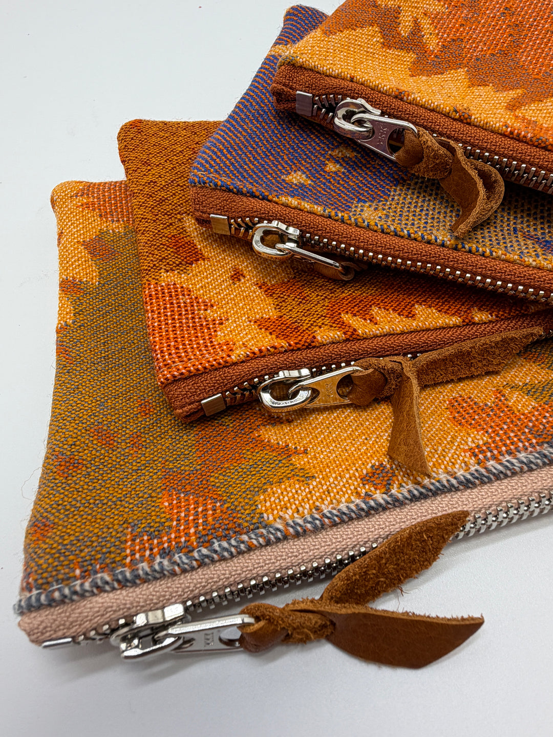 Fabric pouches with zippers in various colors on a white background#color_orange-ferns