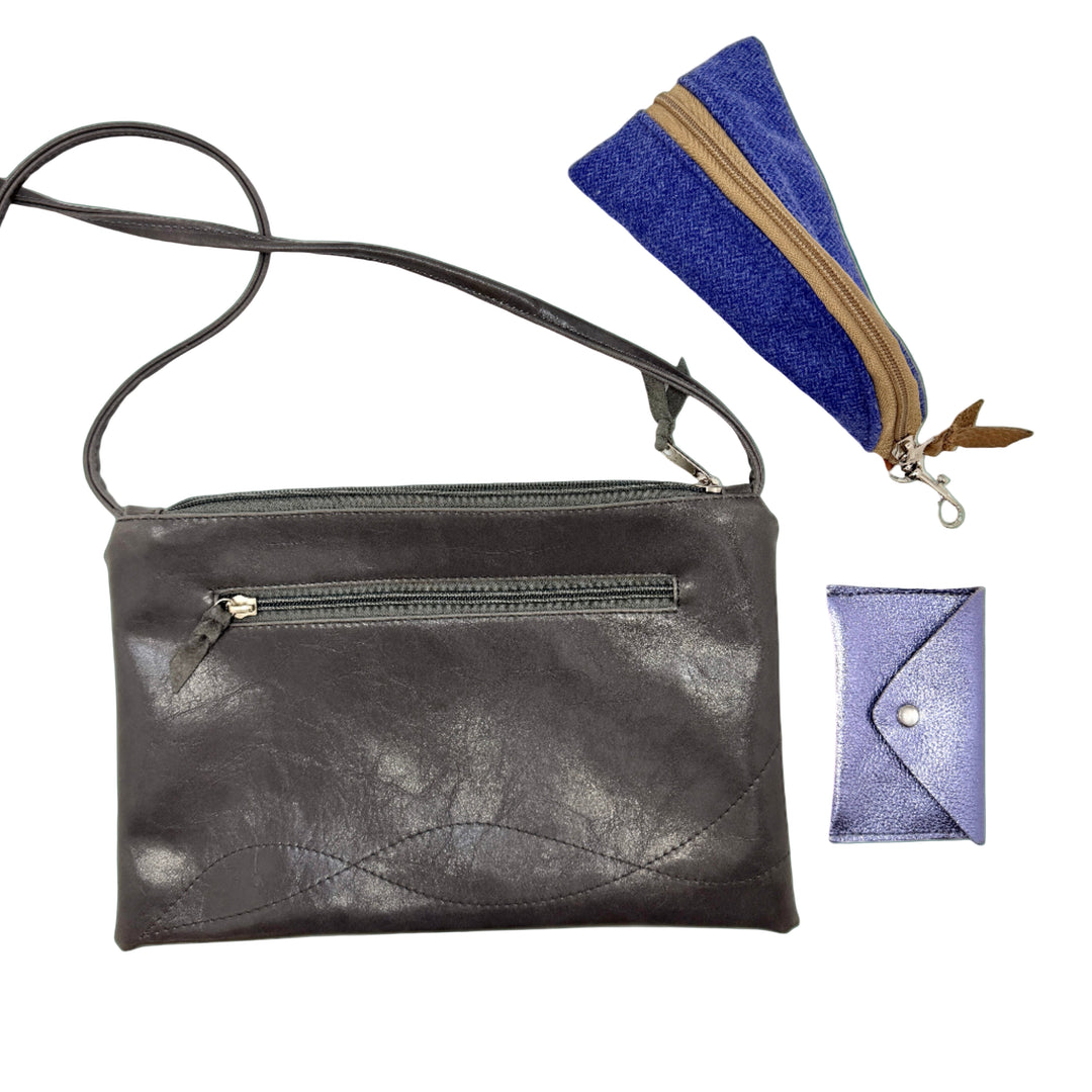 Grey coated canvas crossbody bag with a blue pouch and purple cardholder on a white background