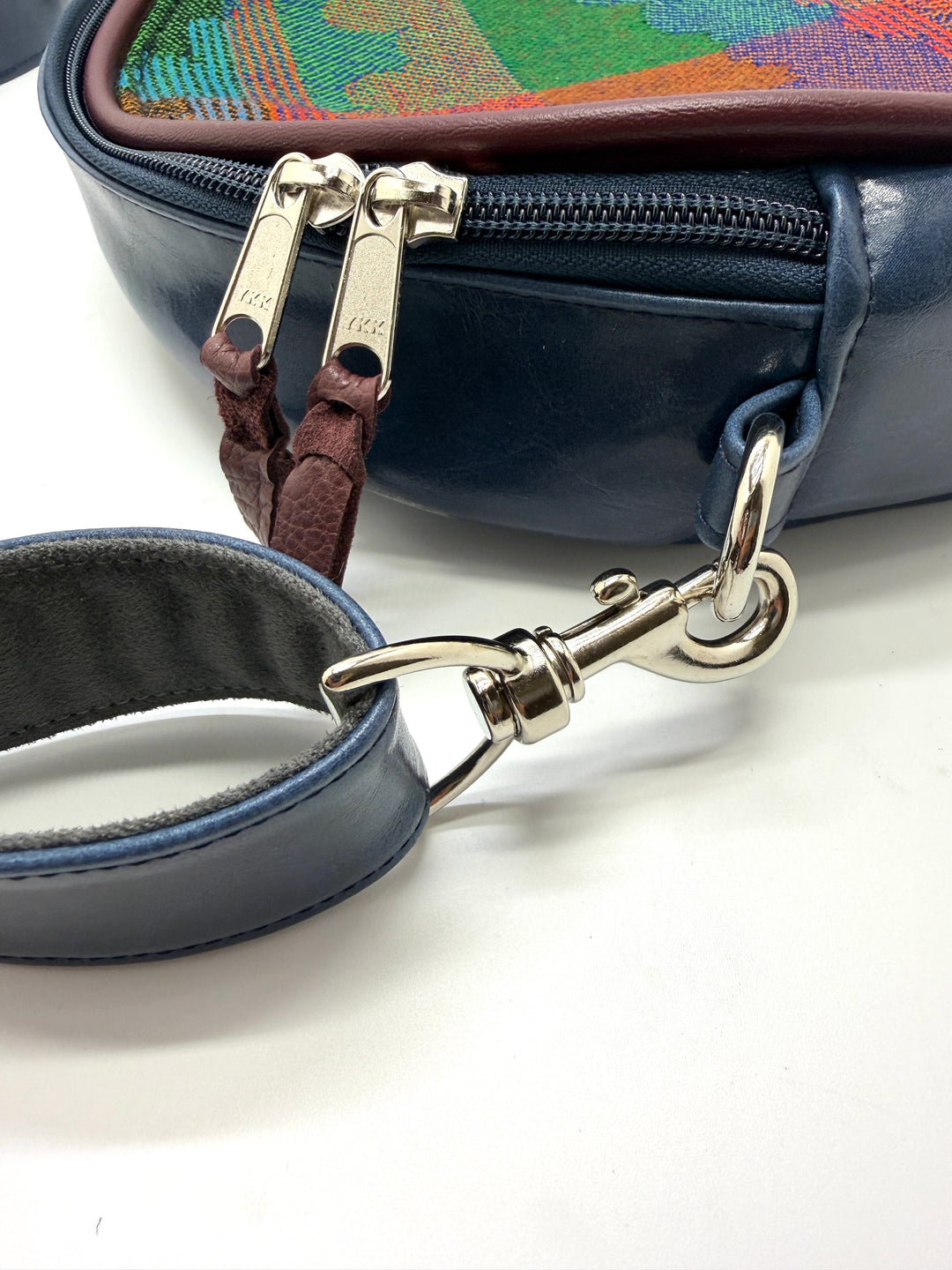 Close-up of a blue handbag with a leather strap and gold clasp on a white background#color_navy-clouds-airplane-fabric