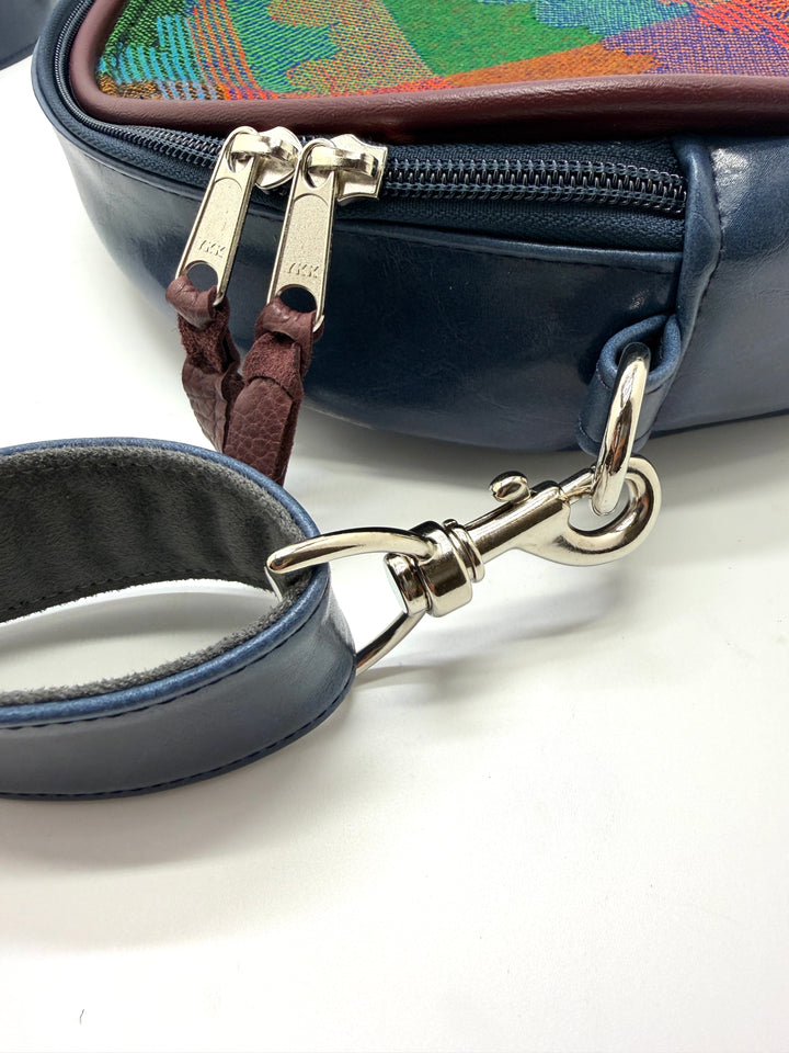 Close-up of a blue handbag with a leather strap and gold clasp on a white background#color_navy-clouds-airplane-fabric
