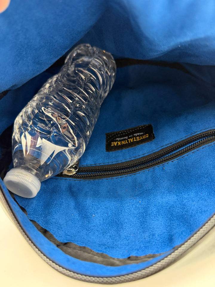 Clear water bottle inside a blue bag with a brand label.#color_black-purple-clouds-airplane-fabric