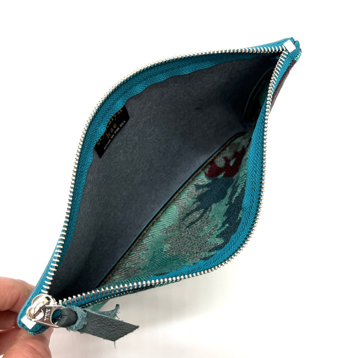 Blue zipper pouch held open to show interior on a white background#color_teal-ferns