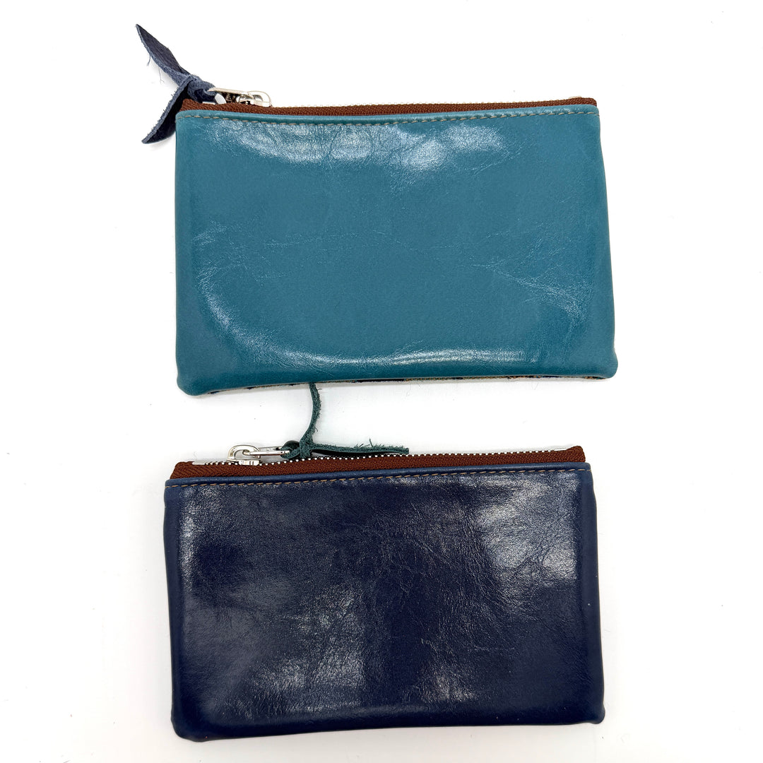Two leather pouches, one blue and one black, on a white background#color_blue-ferns