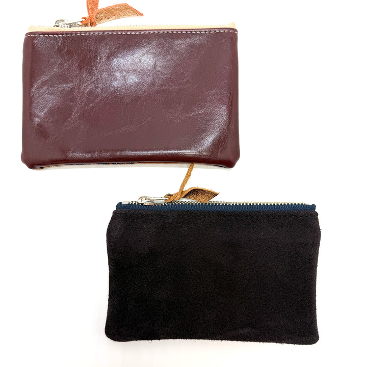 Brown leather wallet and black suede pouch on a white background#color_midnight-ferns
