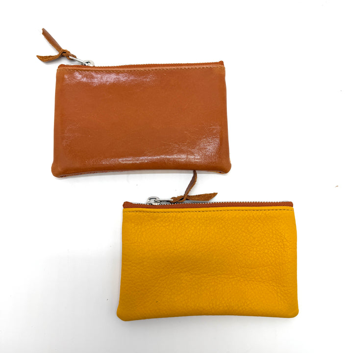 Two leather pouches, one brown and one yellow, on a white background#color_orange-ferns