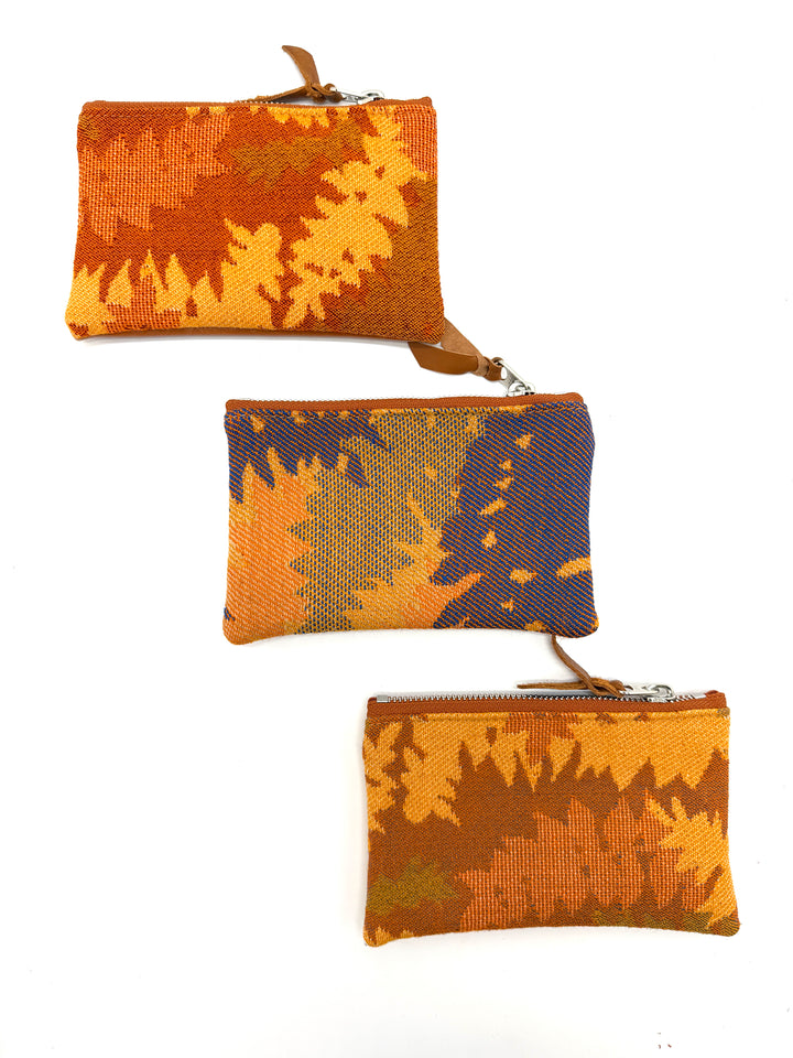 Three woven pouches with autumn-themed patterns on a white background#color_orange-ferns
