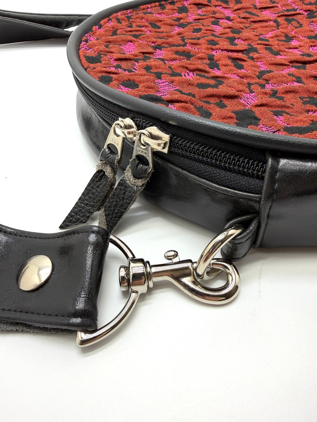 Black handbag with a red and black patterned interior on a white background#color_poppy-leopard