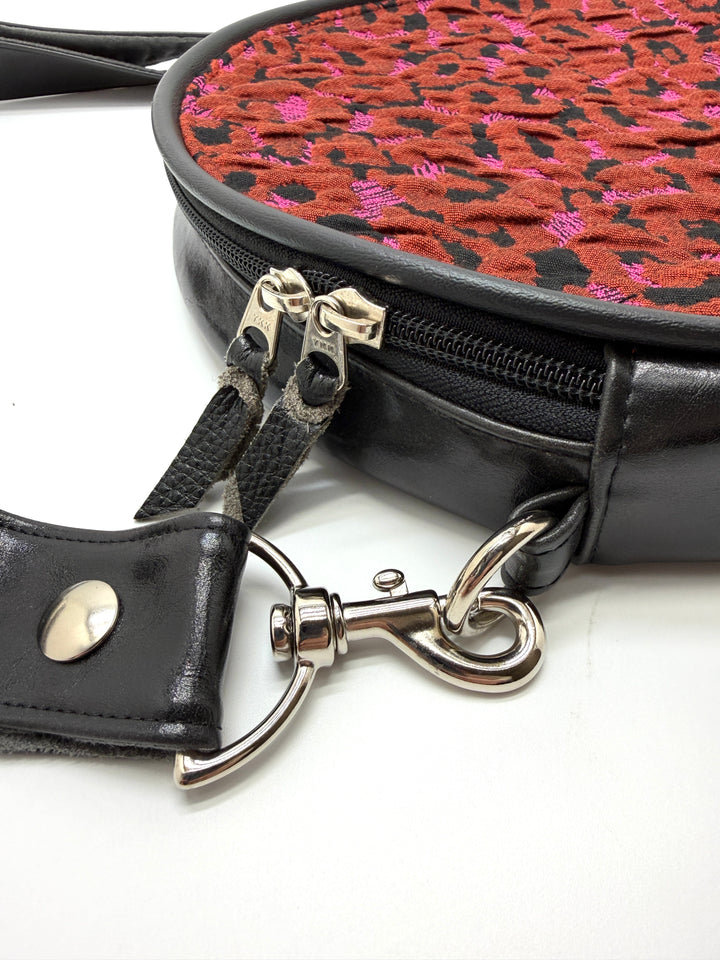 Black handbag with a red and black patterned interior on a white background#color_poppy-leopard