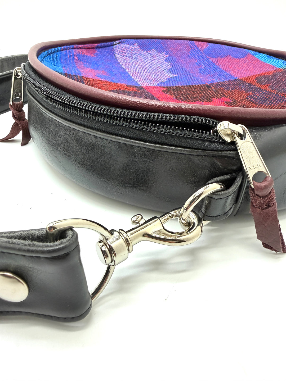 Black leather crossbody bag with colorful interior and detachable strap on a white background#color_black-purple-clouds-airplane-fabric