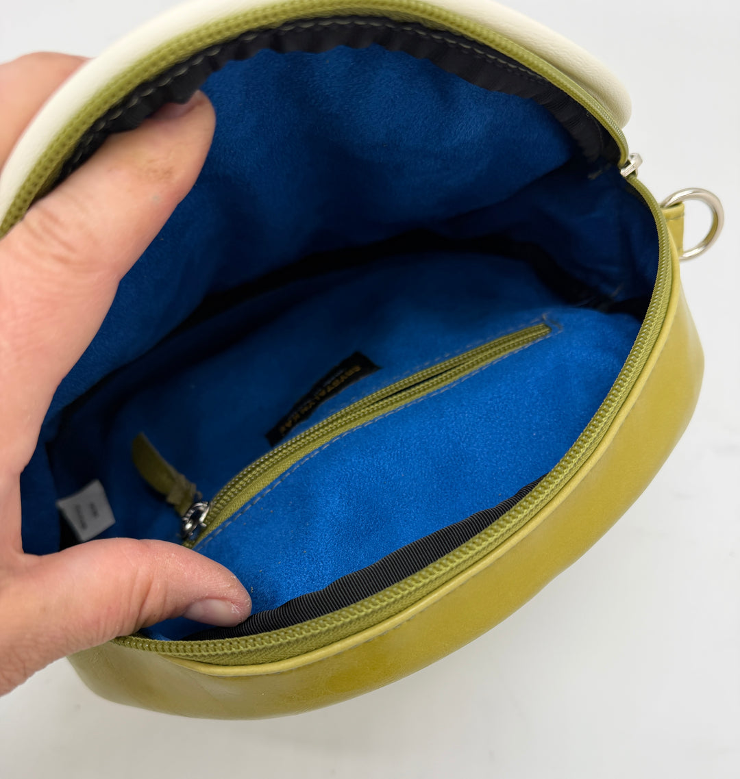 Hand holding a yellow pouch with blue interior on a white background#color_citrine-clouds-airplane-fabric