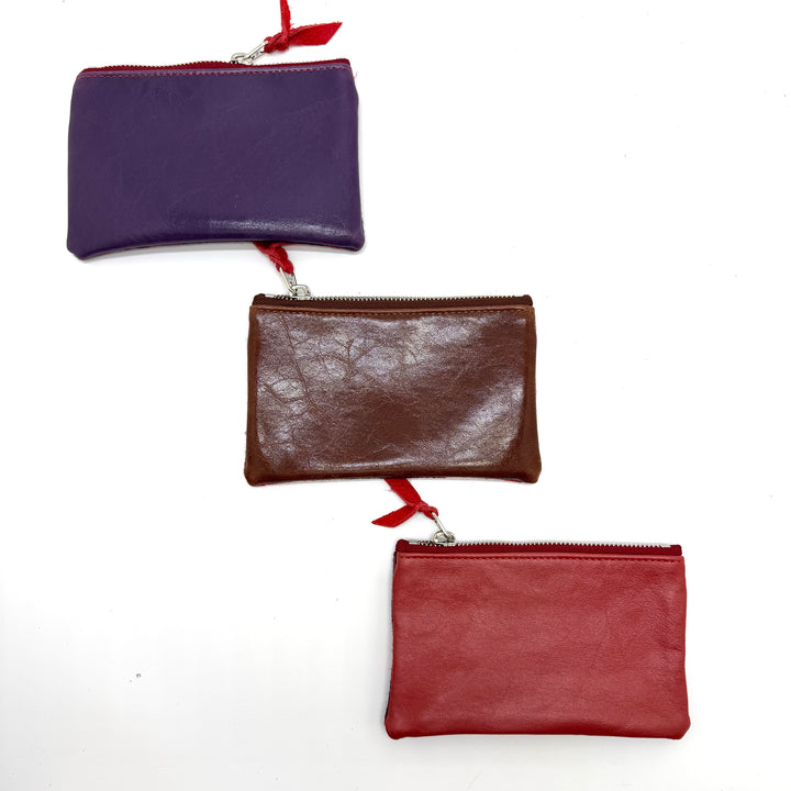 Three leather pouches in purple, brown, and red on a white background#color_red-ferns