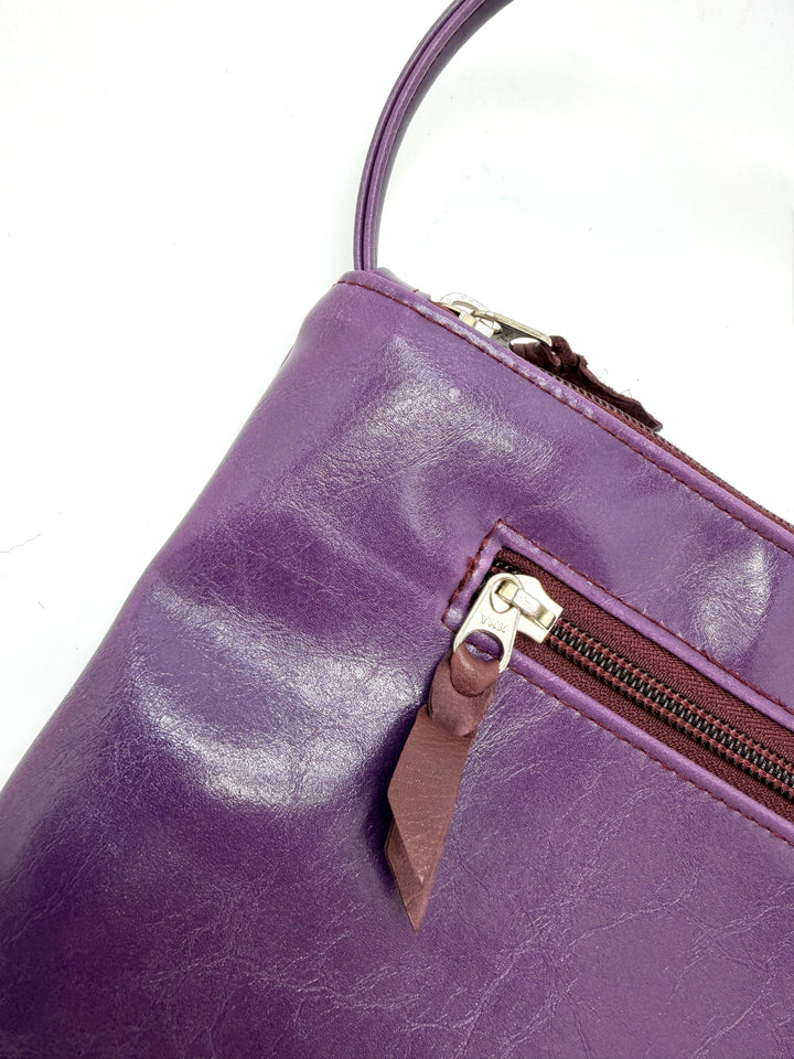 Close-up of a purple leather handbag with a zipper on a white background#color_plum