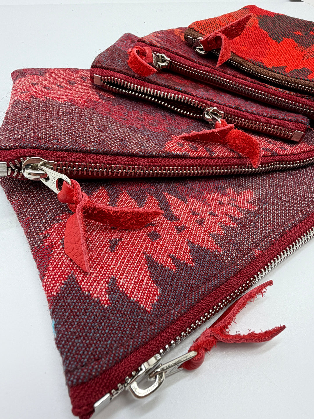 Red and brown patterned pouch with zippers on a white background#color_red-ferns