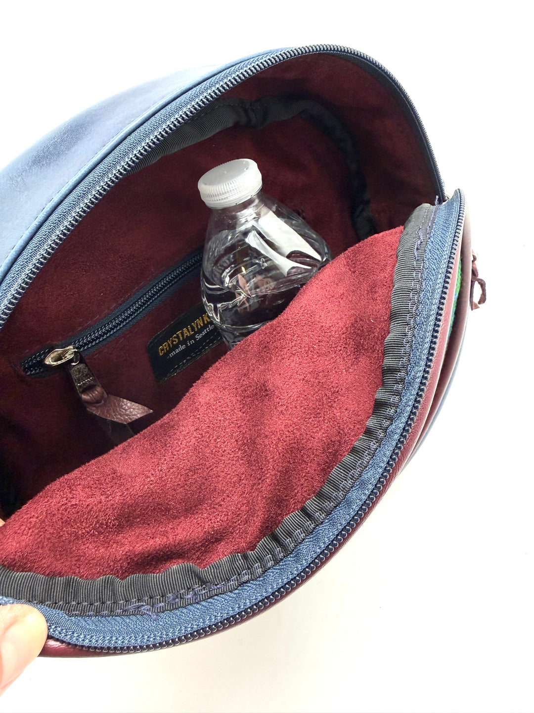 Open bag with a water bottle inside, showing the interior lining.#color_navy-clouds-airplane-fabric
