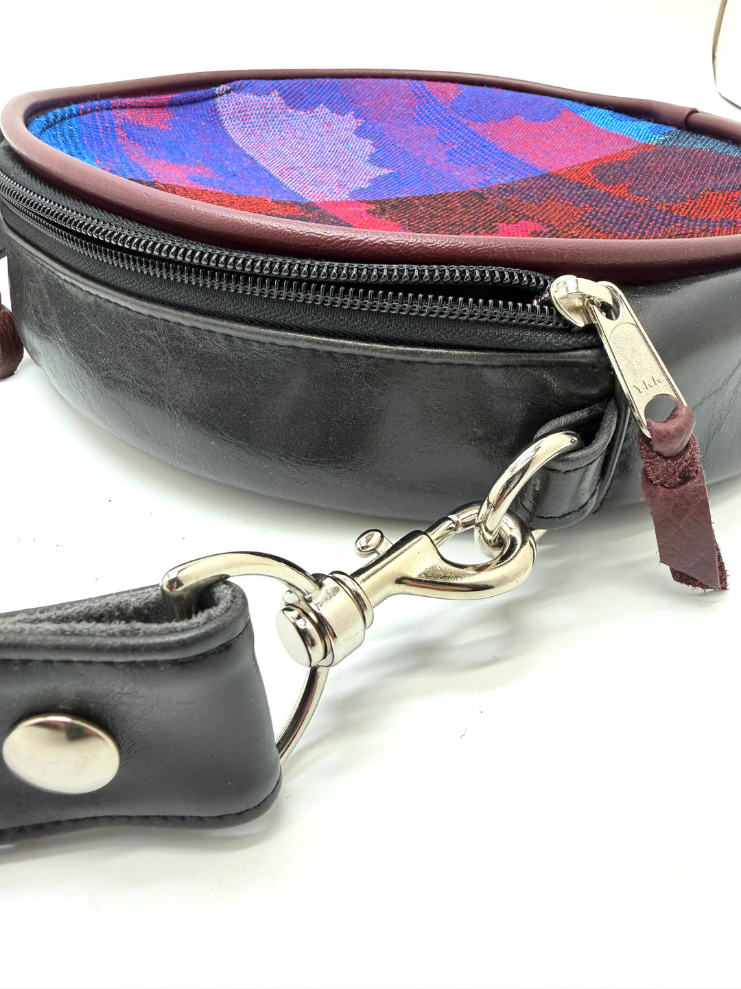 Black leather bag with colorful lining and silver clasp on a white background#color_black-purple-clouds-airplane-fabric
