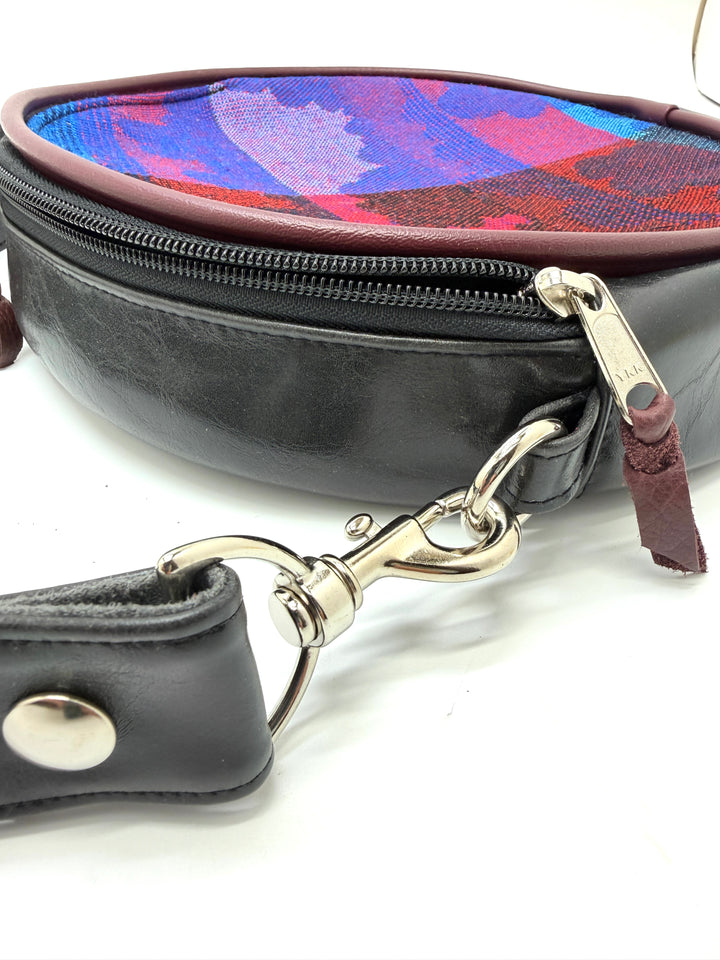 Black leather bag with colorful lining and silver clasp on a white background#color_black-purple-clouds-airplane-fabric