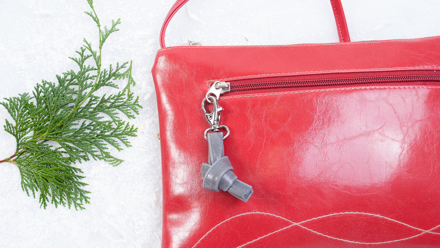 Red leather clutch with a silver charm on a white background