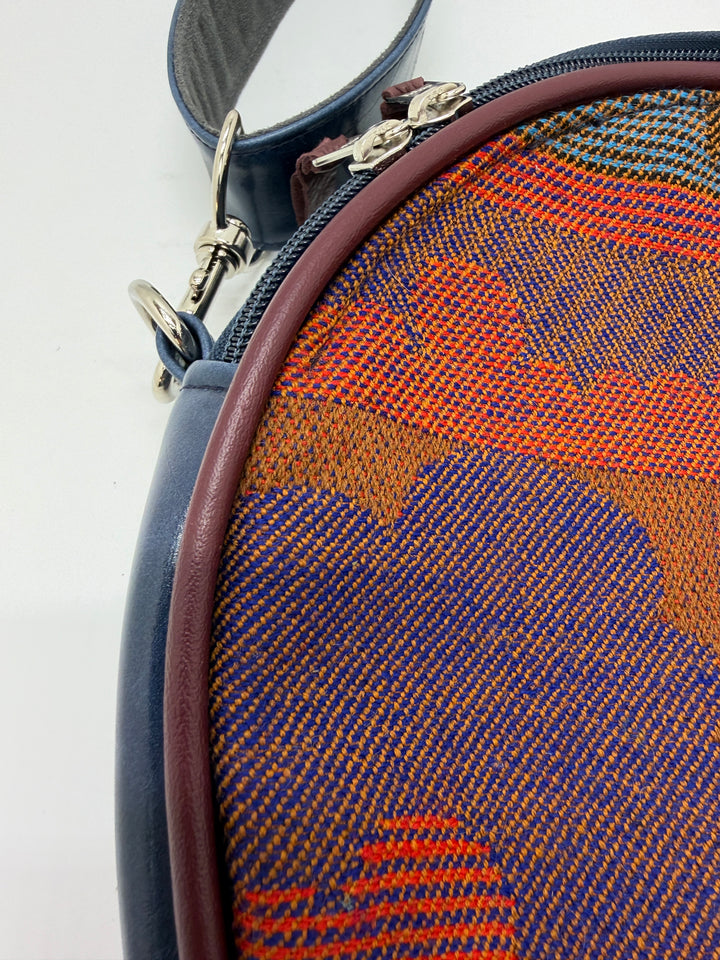 Close-up of a round pouch with a patterned fabric surface and zipper.#color_navy-clouds-airplane-fabric