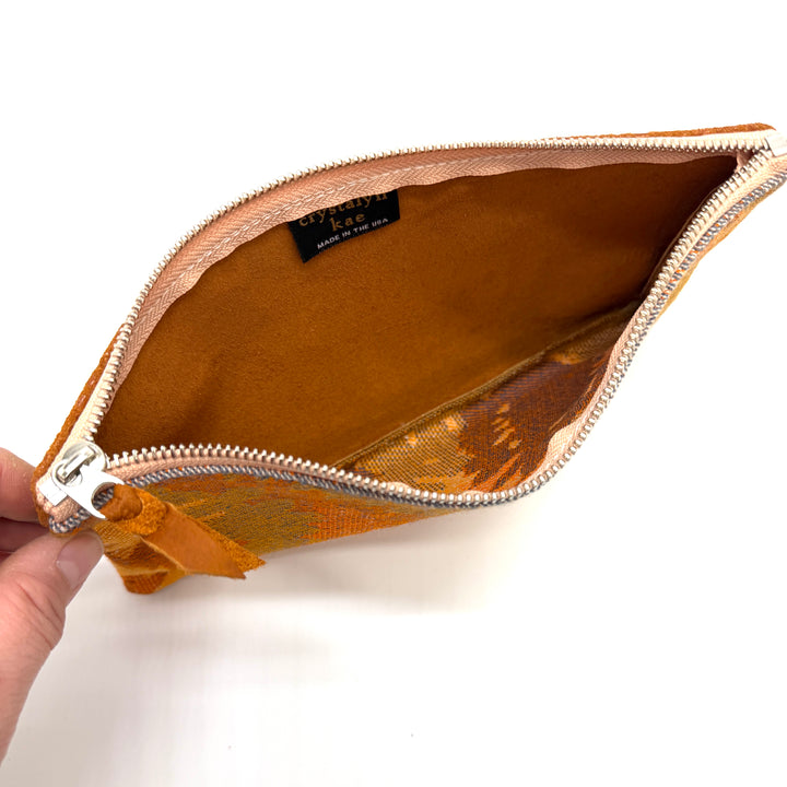 Brown pouch with a visible brand label on a white background#color_orange-ferns