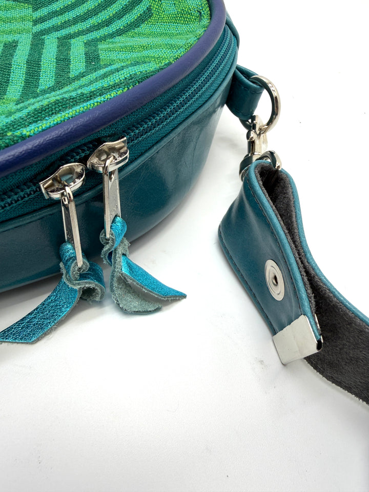 Close-up of a blue handbag with a decorative strap on a white background#color_navy-teal-hexagon-airplane-fabric