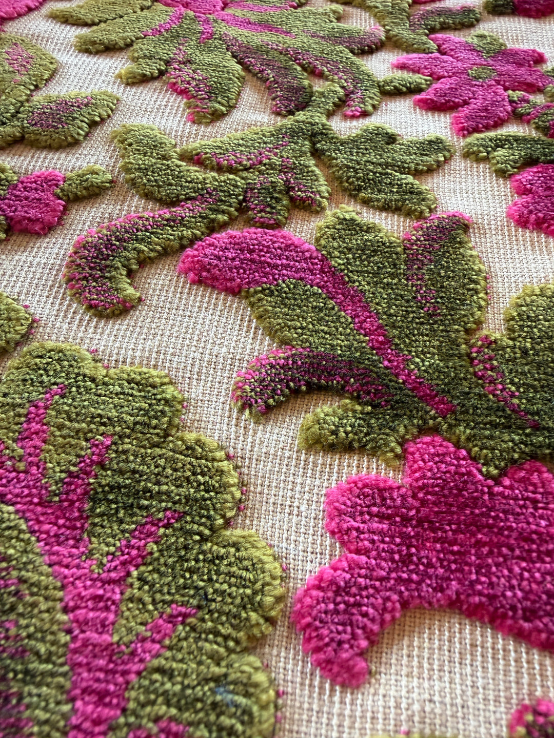 Close-up of a textured fabric with pink and green floral patterns.#color_fuchsia-moss-velvet-floral