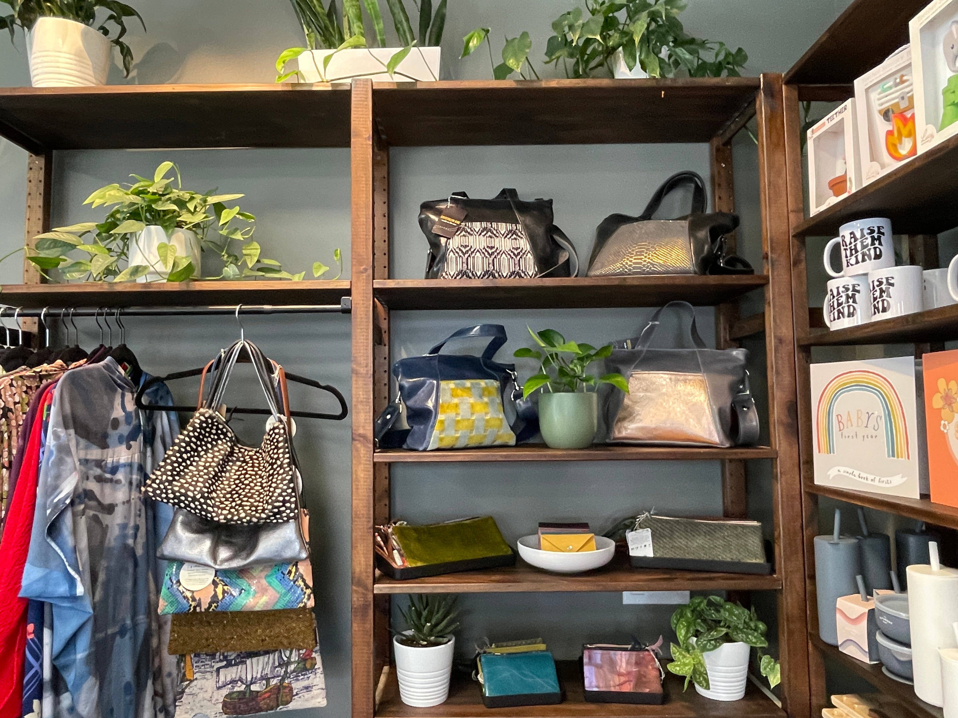 Shelves displaying handbags, clothing, and decorative items in a store setting.
