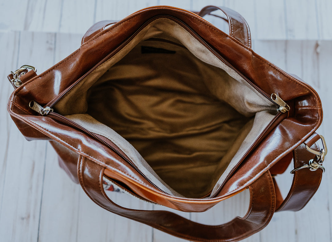 Brown leather handbag on a wooden surface#color_ale-brown