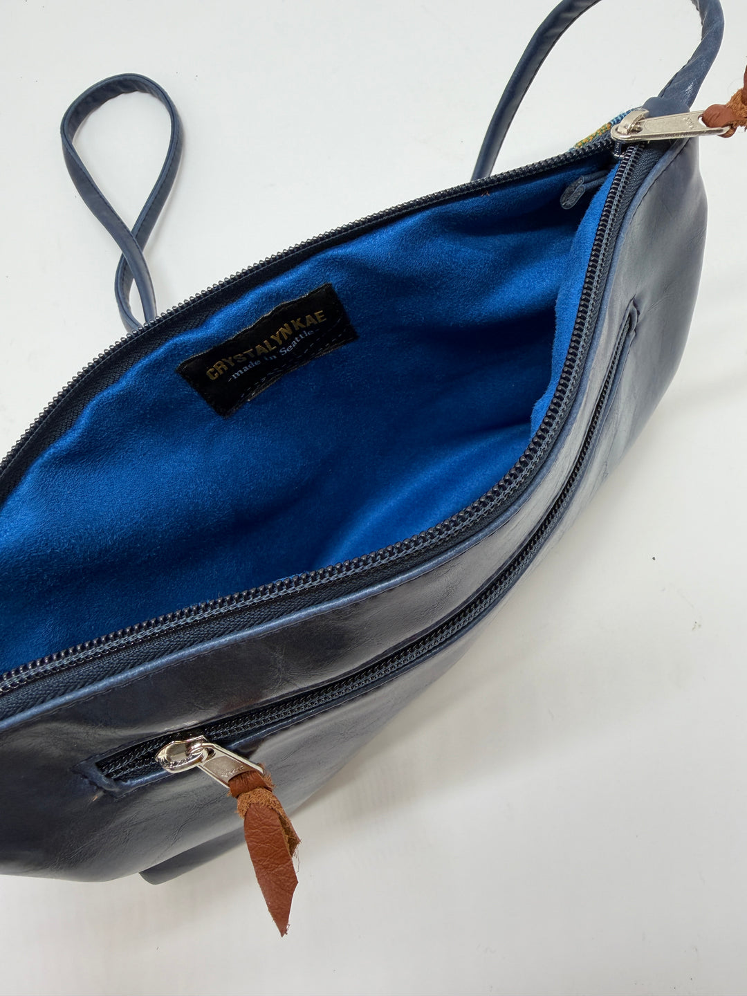 Blue interior of a leather bag with vintage airplane fabric visible brand label on a white background#color_western-airlines-paisley-blue-gold
