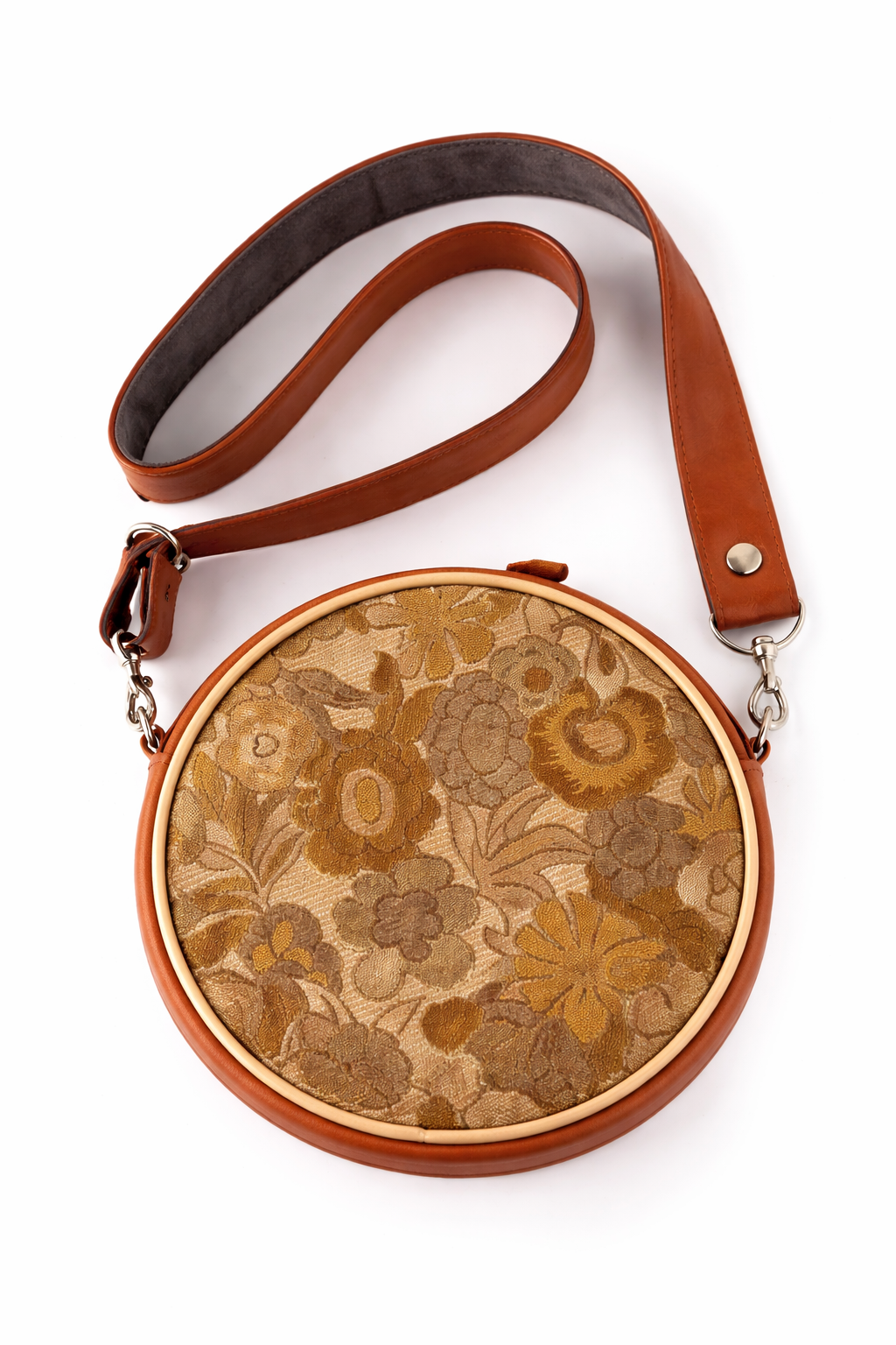 Round handbag with floral pattern and brown leather strap on a white background##color_sunset-bloom
