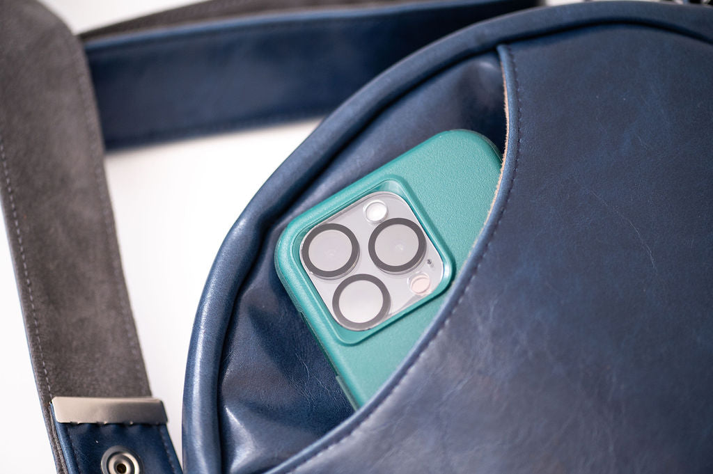 Teal phone case with camera lens design inside a blue leather bag#color_nautical-sailboat-barkcloth