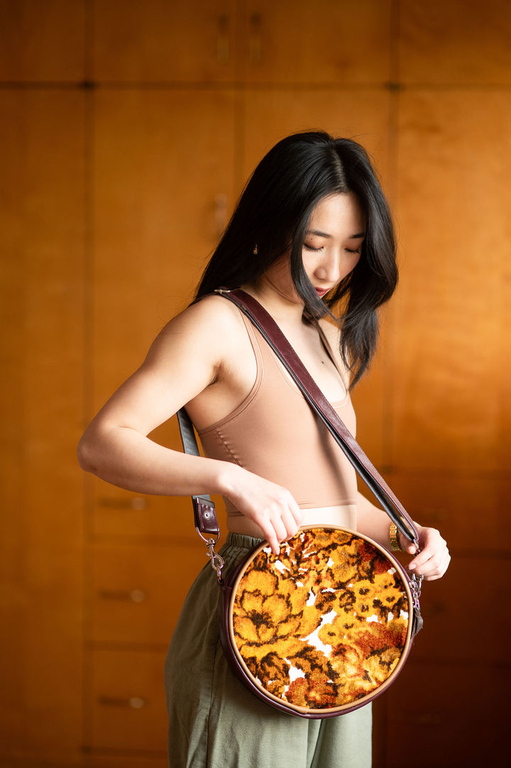 Woman holding a round dish with food against a warm-toned background#color_golden-floral-chenille