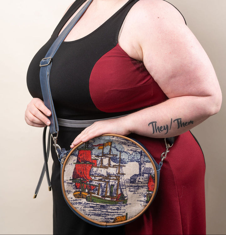 Person holding a crossbody bag with embroidery design against a plain background#color_nautical-sailboat-barkcloth