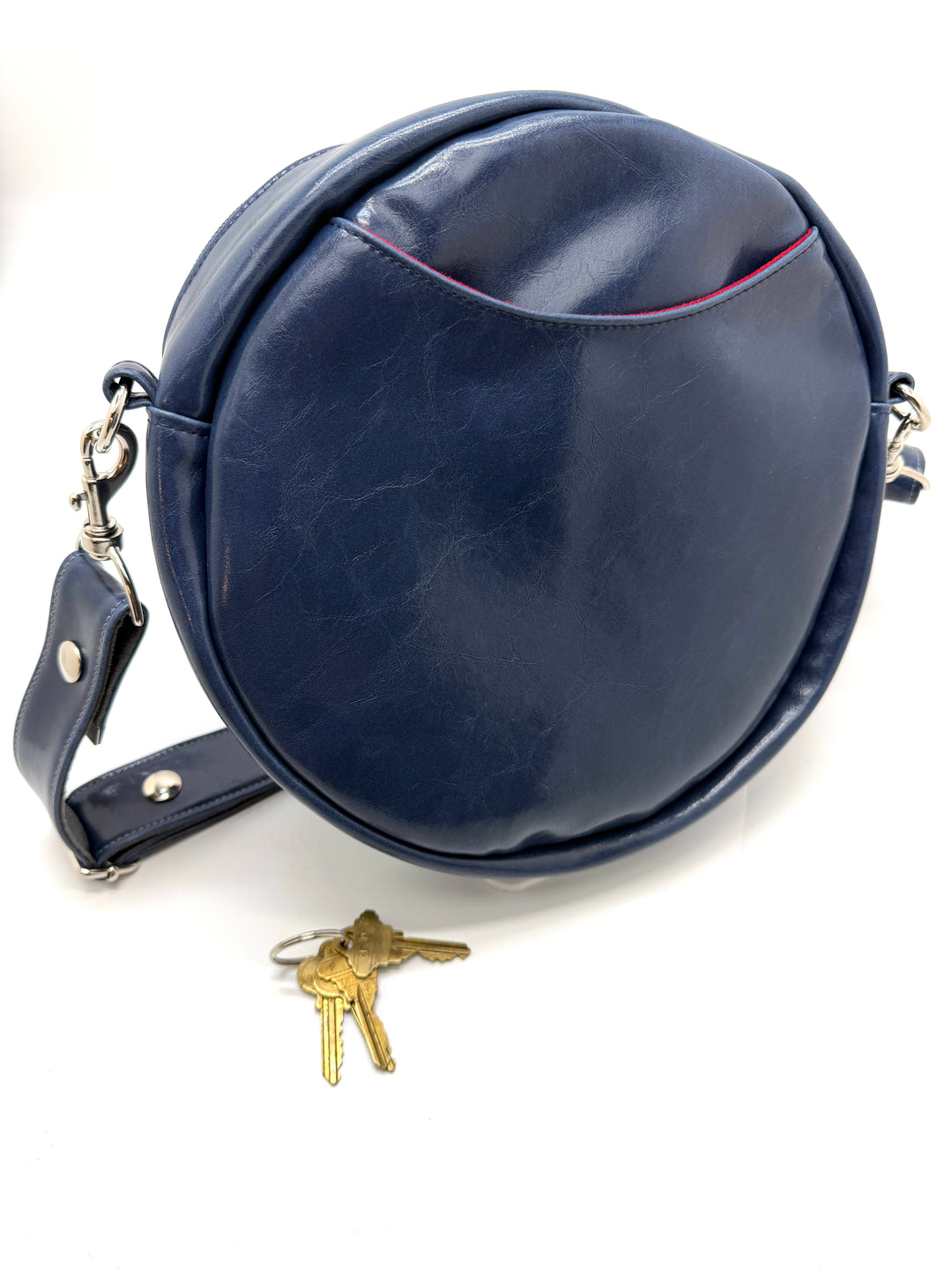 Blue round leather bag with a strap and keys on a white backgroundRound handbag with colorful abstract pattern on a white background#color_palm-fronds-cool