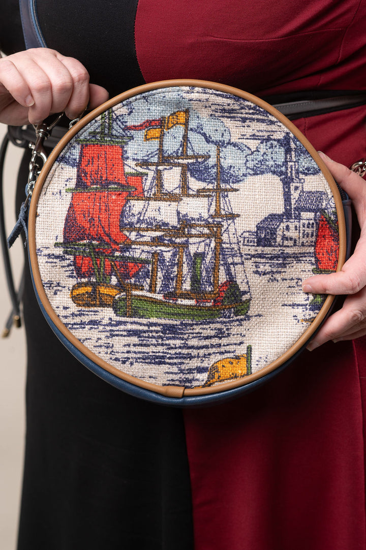 Embroidery hoop with a ship design held by a person wearing a red garment#color_nautical-sailboat-barkcloth