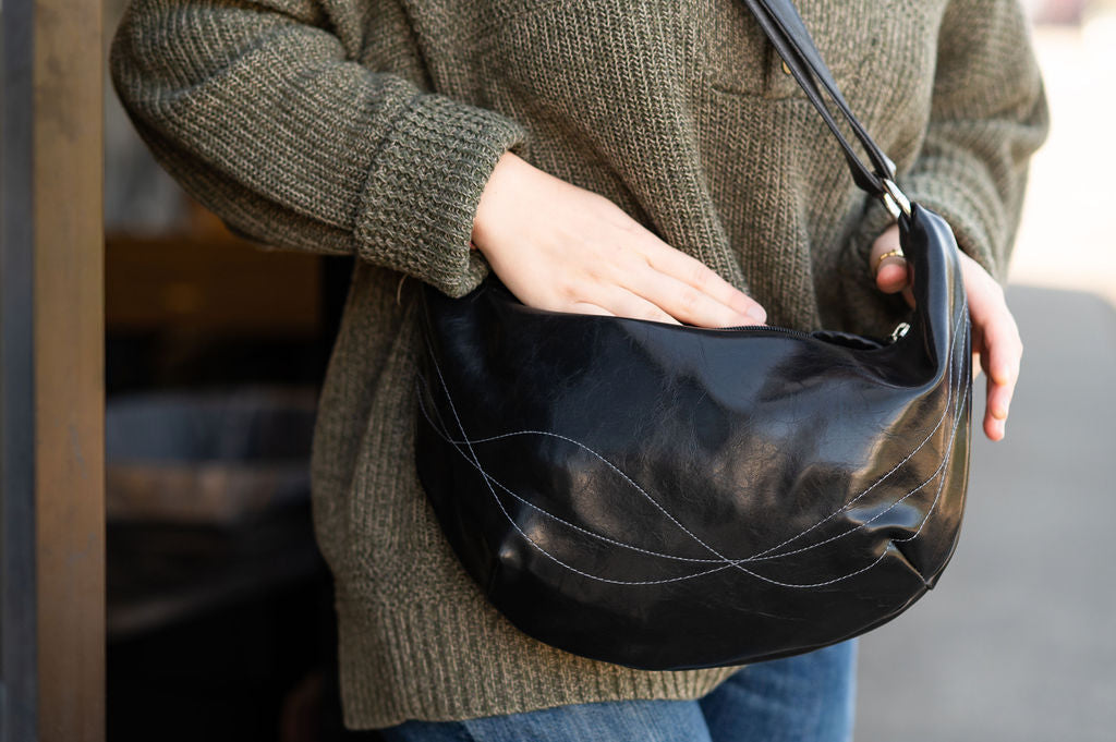 Person holding a black handbag with a blurred background#color_black