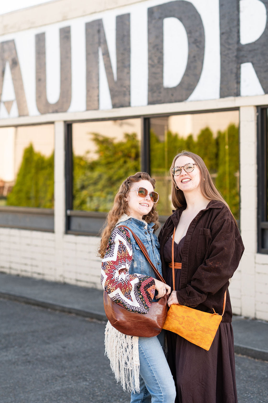 Two women standing in front of a building with large letters spelling 'LAUNDRY'.#color_ale-brown
