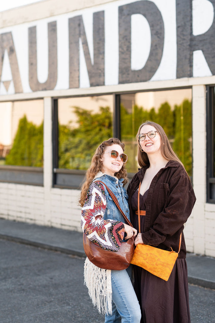 Two women standing in front of a building with large letters spelling 'LAUNDRY'.#color_ale-brown