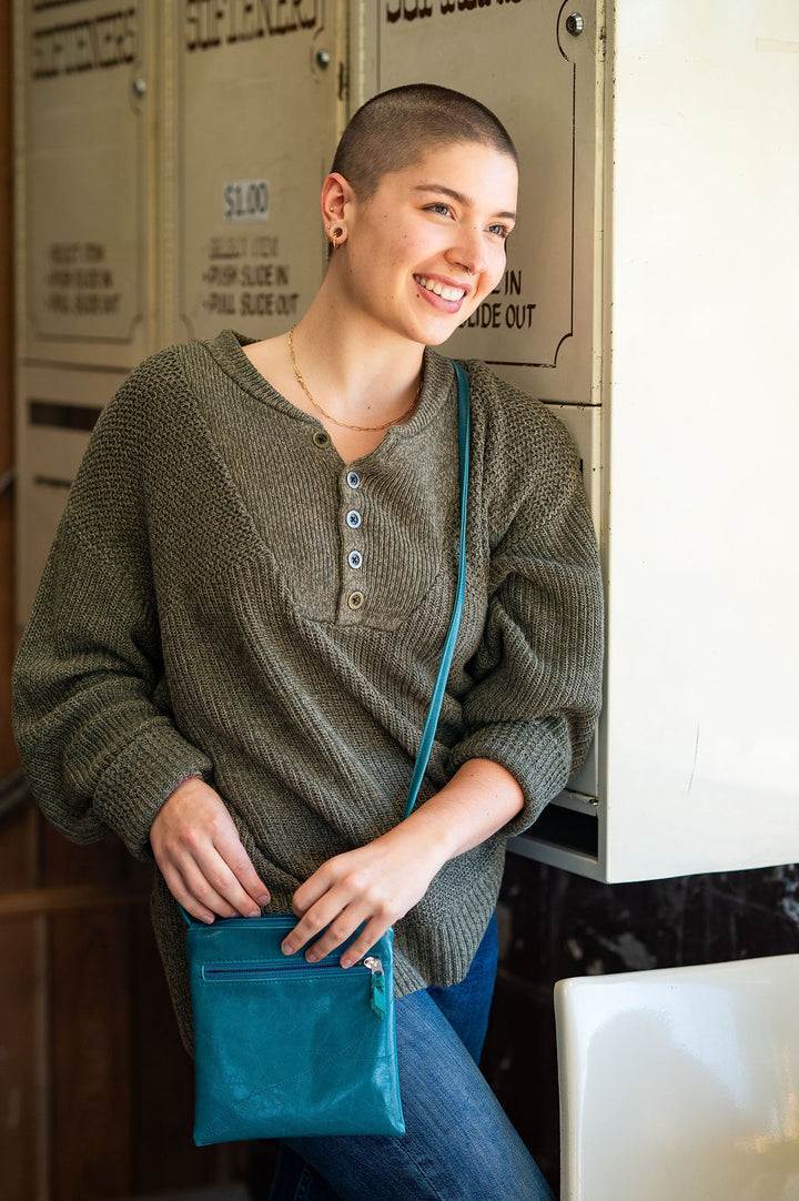 Woman holding a blue bag in an indoor setting#color_teal