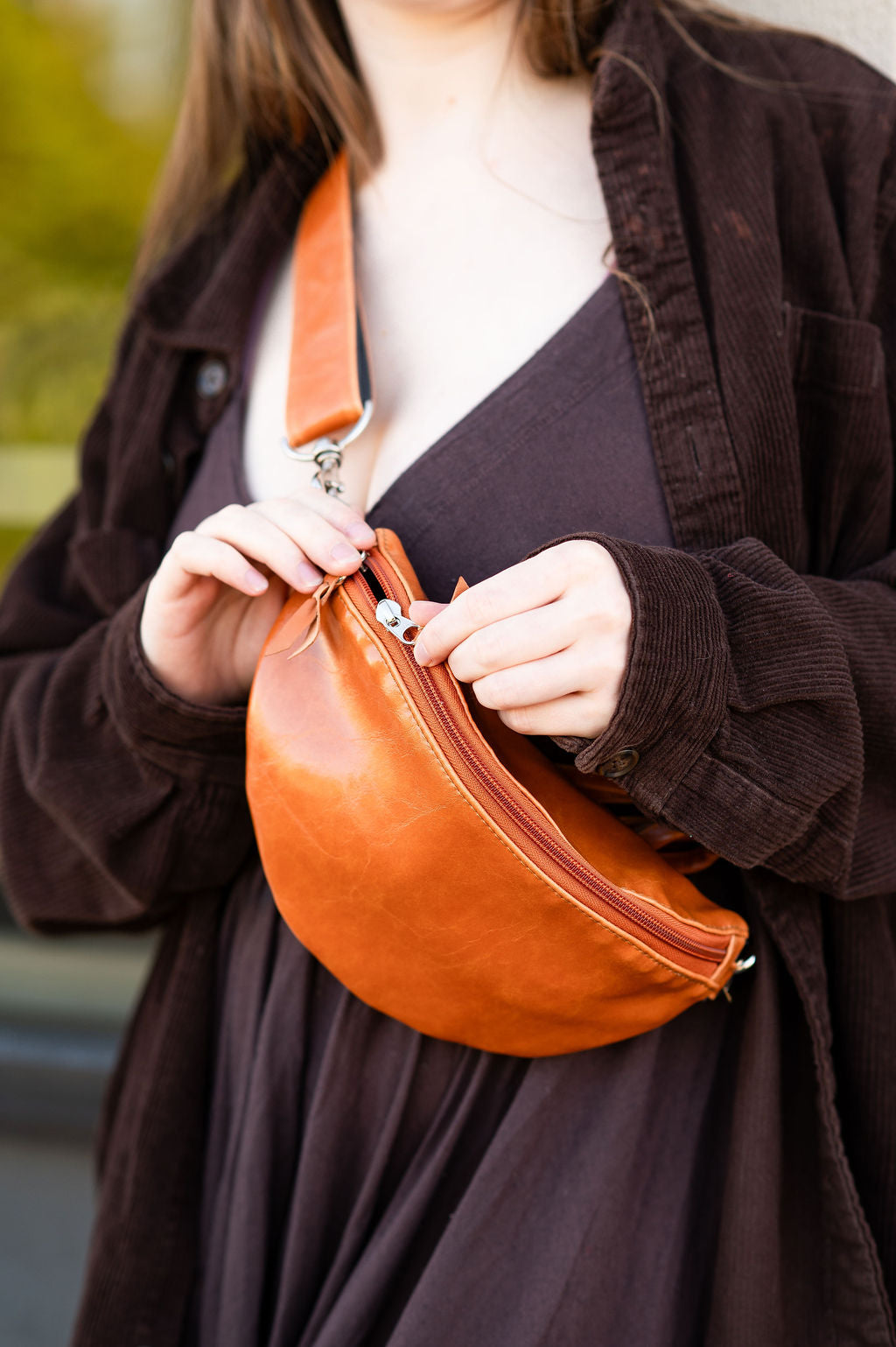 Person holding a brown leather bag with a blurred background#color_butterscotch