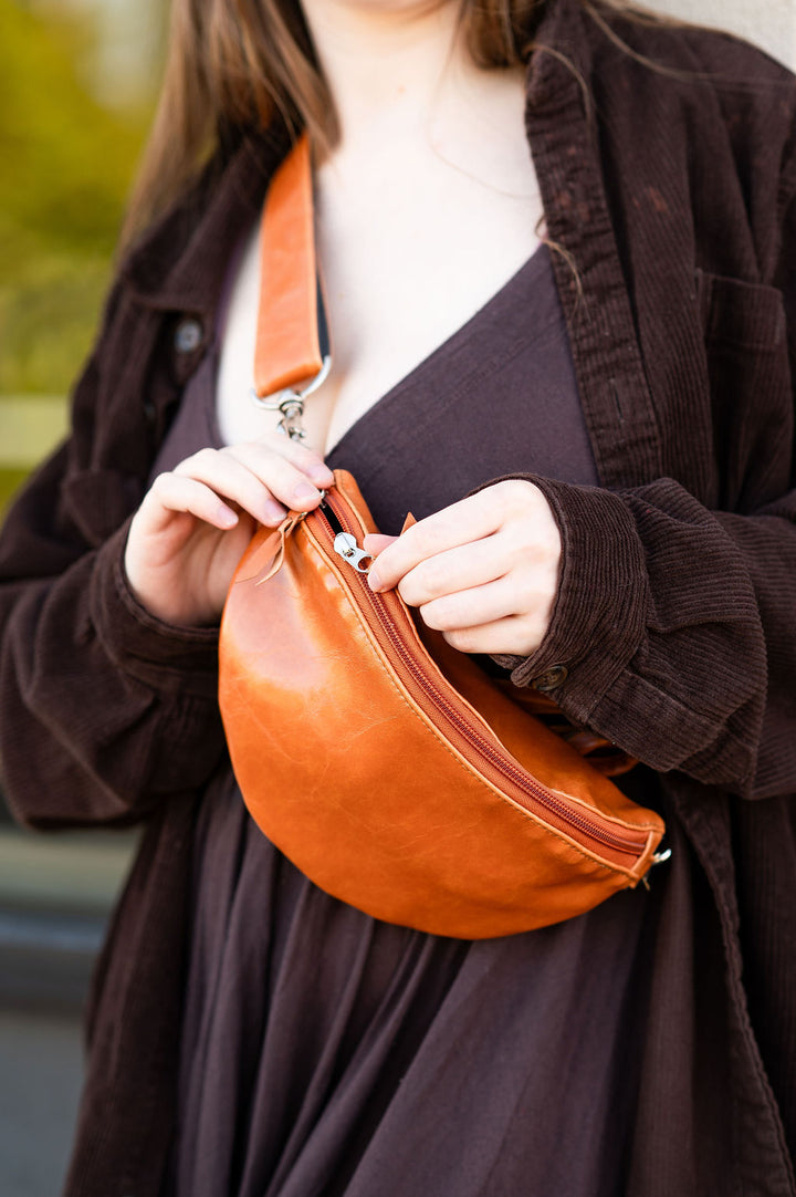 Person holding a brown leather bag with a blurred background#color_butterscotch