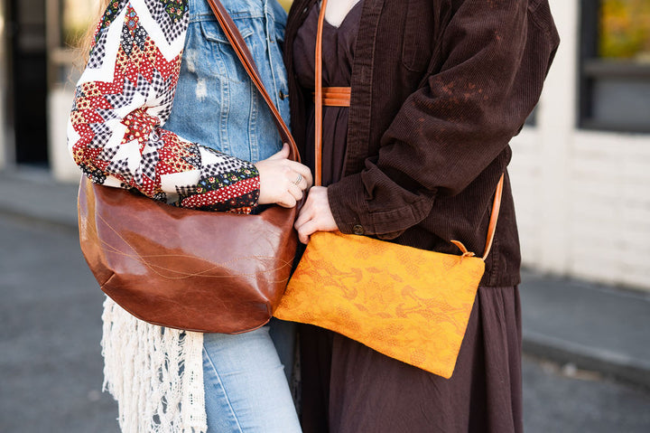 Two people holding leather bags on a street.#color_egypt-air-orange-gold