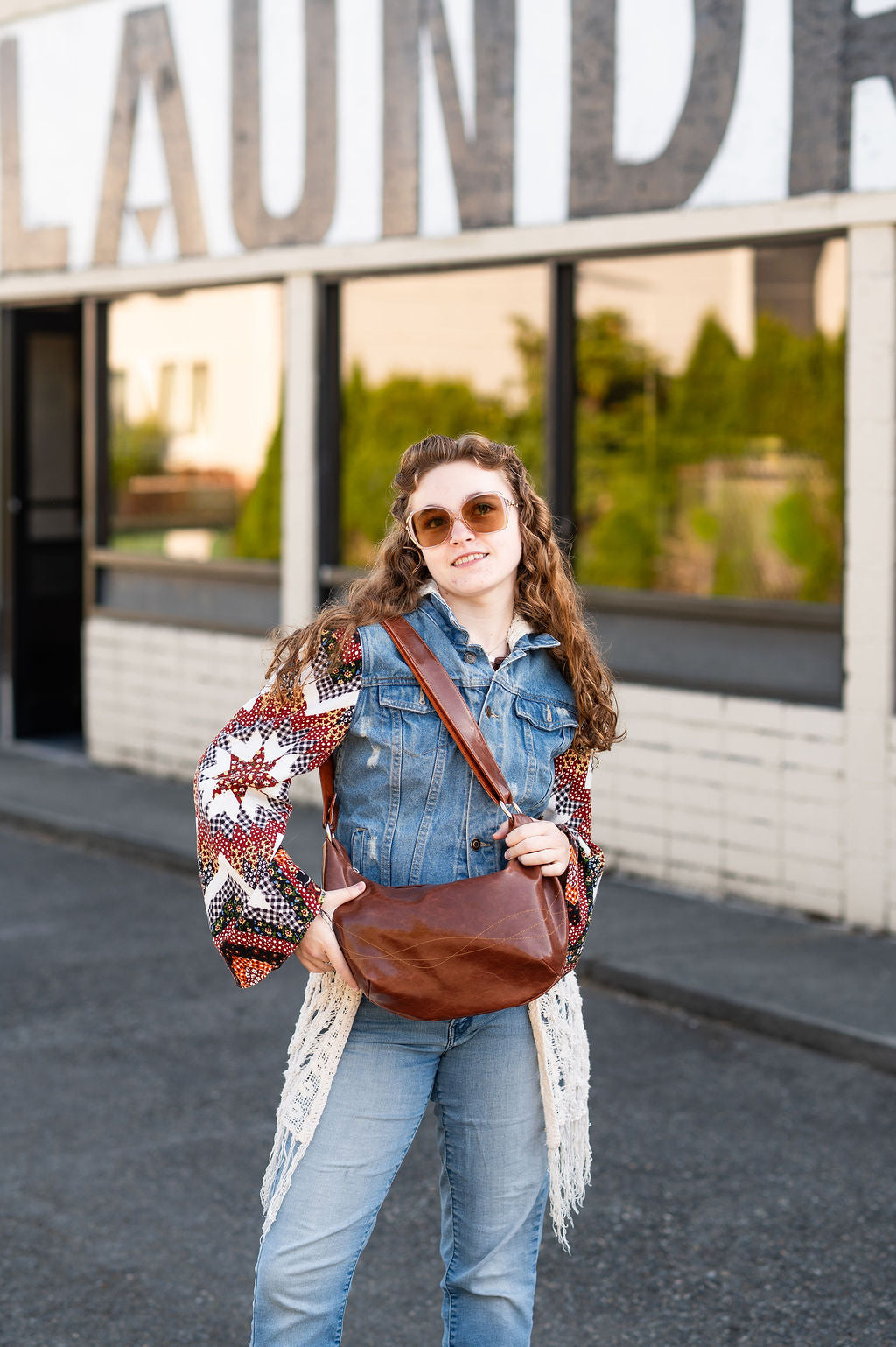 Woman standing in front of a building with large letters spelling 'LAUNDRY'.#color_ale-brown