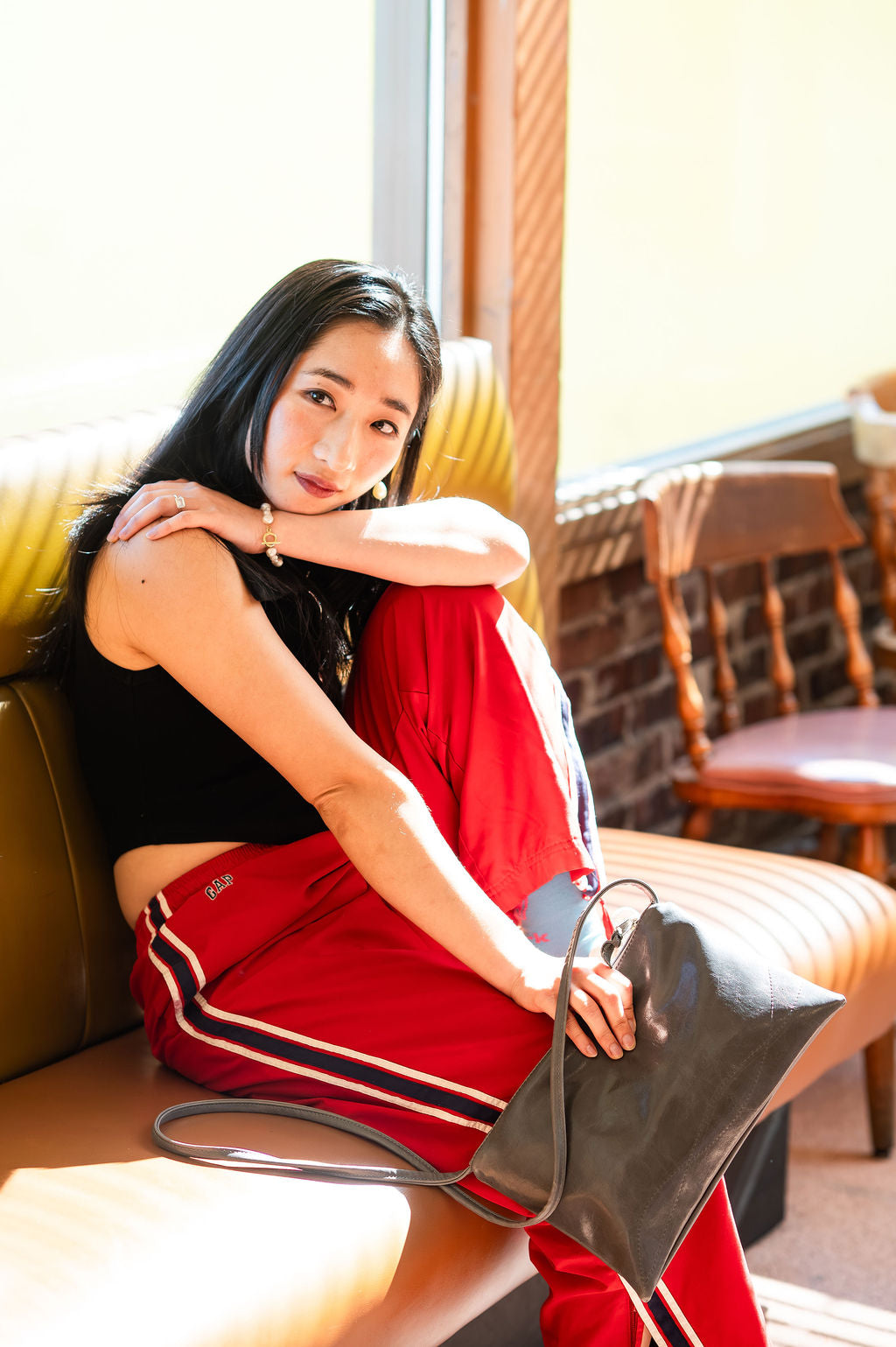 Woman sitting on a couch holding a handbag in a casual setting#color_grey