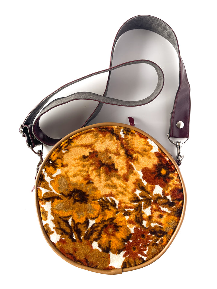 Round floral-patterned handbag with a strap on a white background#color_golden-floral-chenille