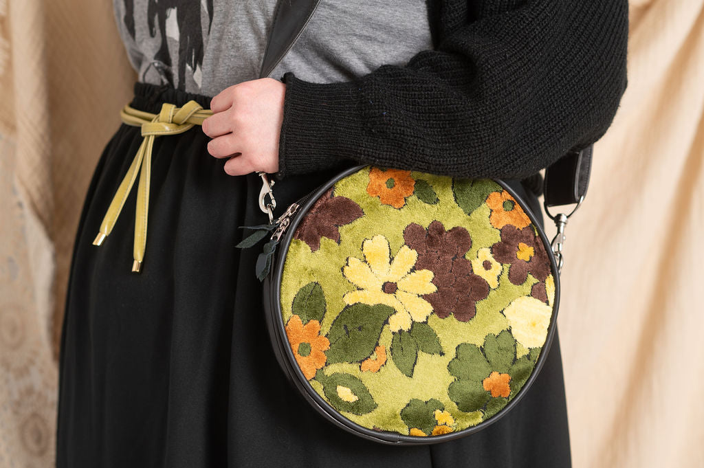 Round floral handbag held by a plus-size person with a neutral background