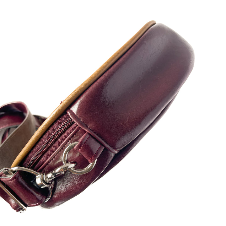 Close-up of a maroon leather handbag with a gold zipper on a white background#color_golden-floral-chenille