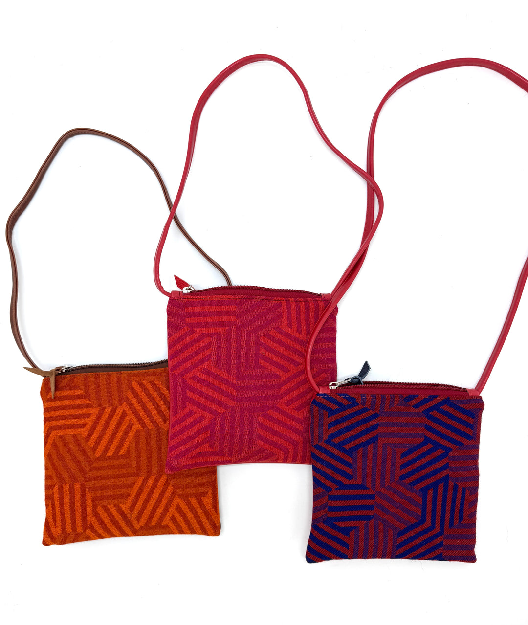 Three hexagon-patterned crossbody bags in red, orange, and blue on a white background#color_hexagon-warm