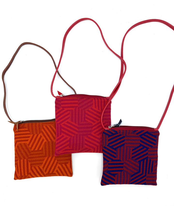 Three hexagon-patterned crossbody bags in red, orange, and blue on a white background#color_hexagon-warm
